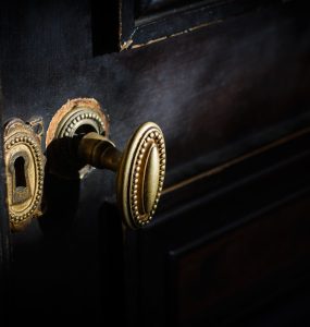 side view detail of vintage antique golden door know with metallic carvings and keyhole on dark background natural lightning