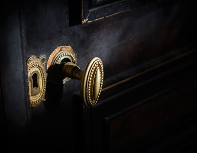side view detail of vintage antique golden door know with metallic carvings and keyhole on dark background natural lightning
