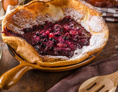 Dutch baby pancake with berries, delicious pancake baked in oven on iron skillet