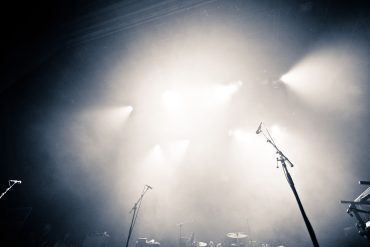 Empty illuminated stage with drumkit, guitar and microphones