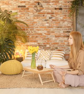 Young girl meditating in cozy natural room with red brick wall