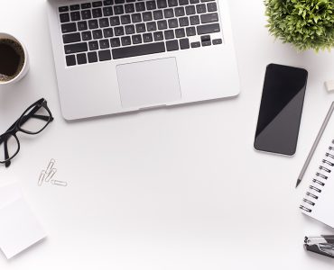 Business concept. Laptop with office supplies on white table with copy space