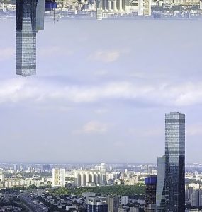 Panoramic aerial view of skyscrapers in the financial district, England, United Kingdom, mirror horizon effect. Modern tall buildings on cloudy sky background, inception theme.