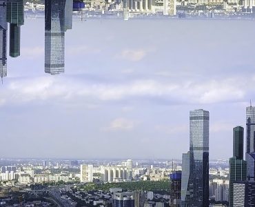 Panoramic aerial view of skyscrapers in the financial district, England, United Kingdom, mirror horizon effect. Modern tall buildings on cloudy sky background, inception theme.